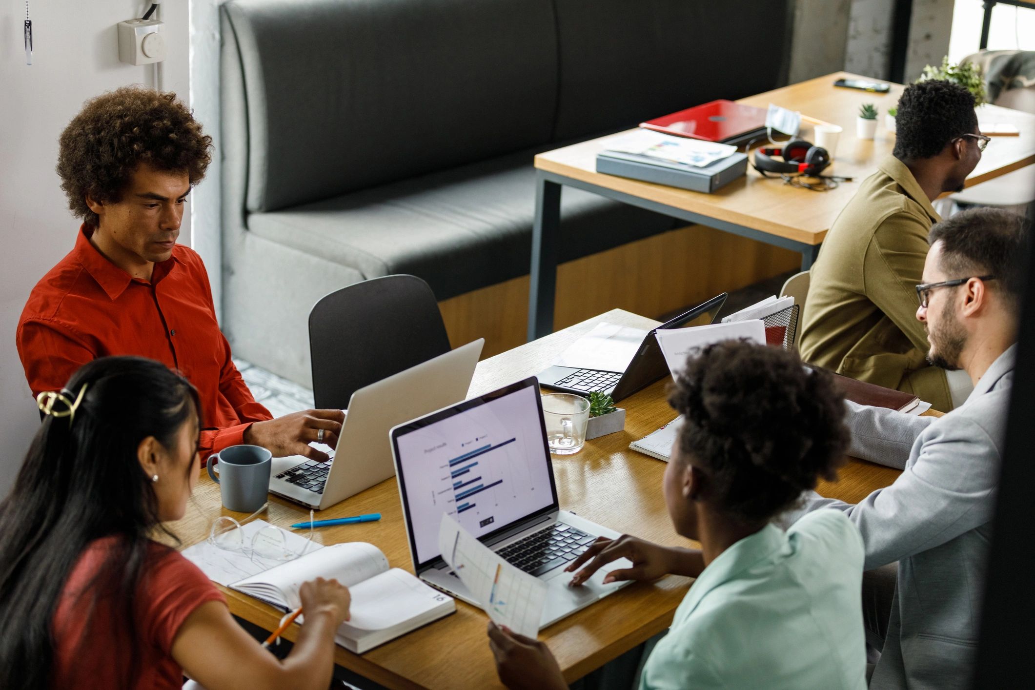 Aerial view of a team collaborating in an office with notebooks and a laptop