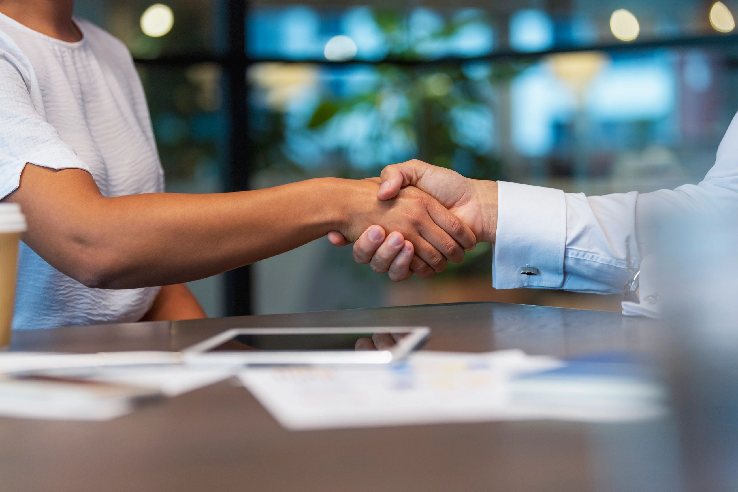 Business partners shaking hands across a table