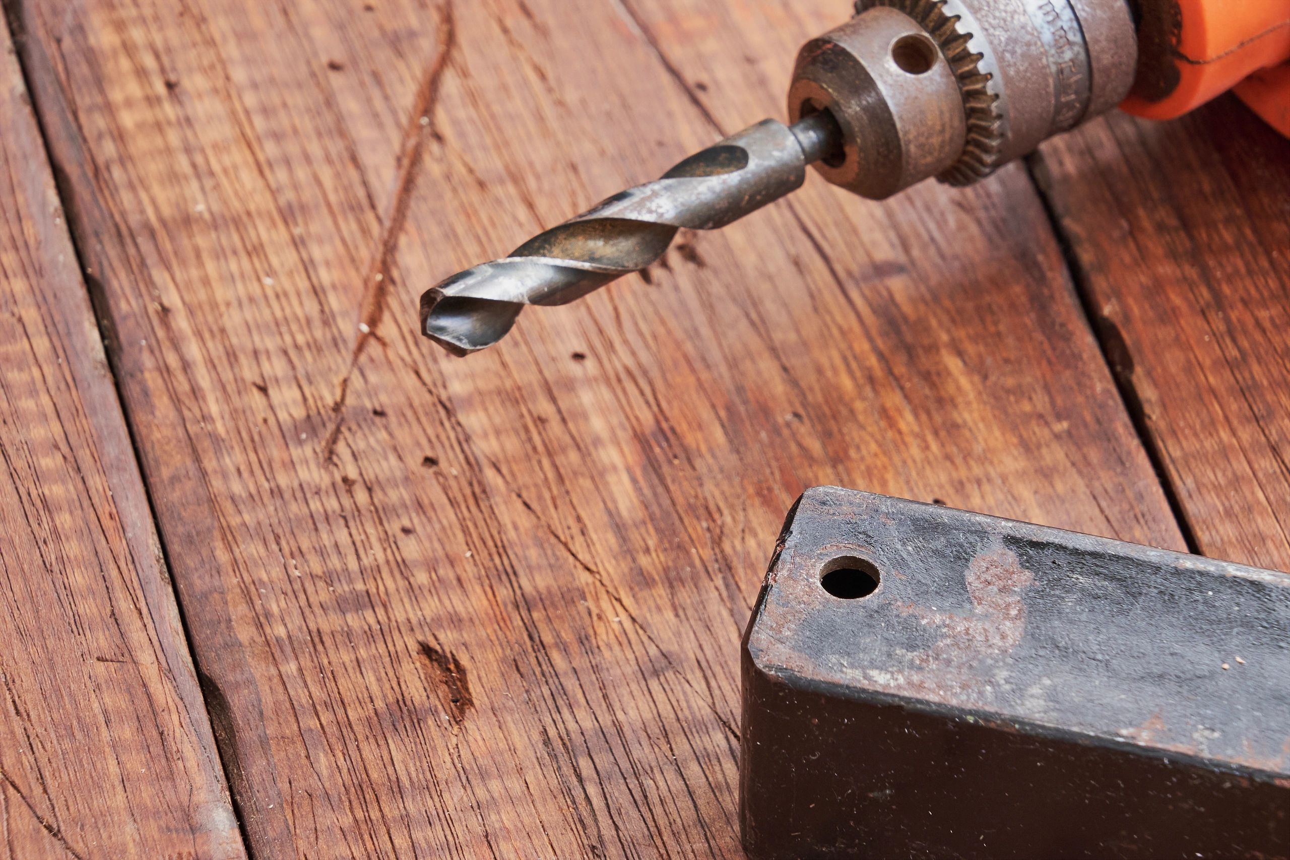 Close-up of drill bit and metal piece on workbench