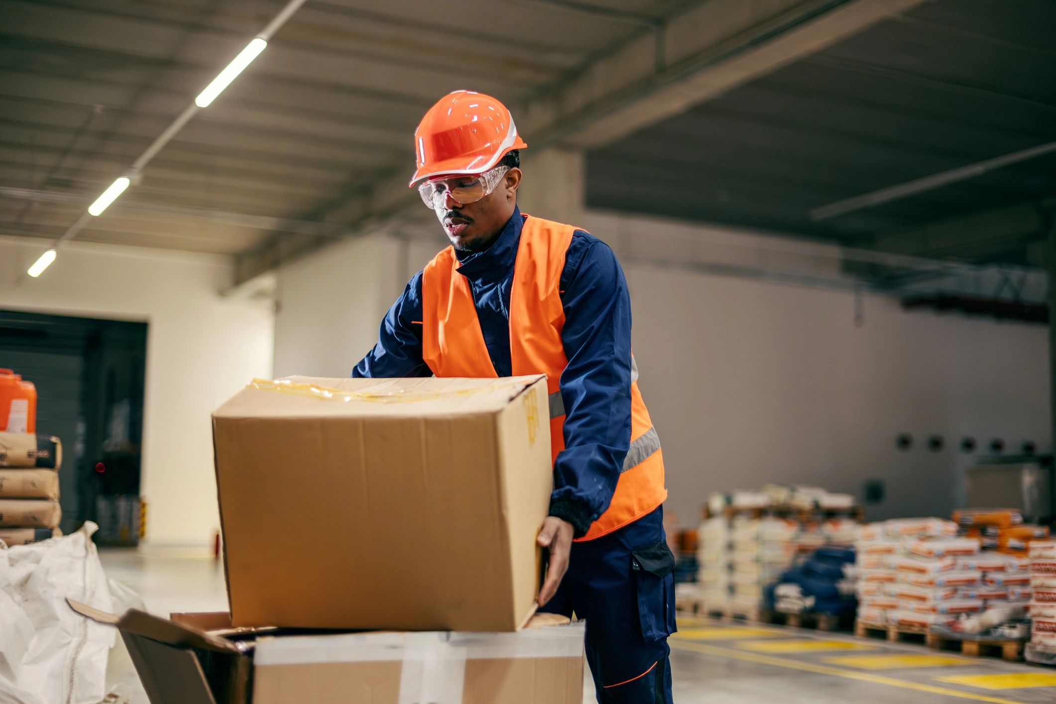 Warehouse worker in safety gear handling a box
