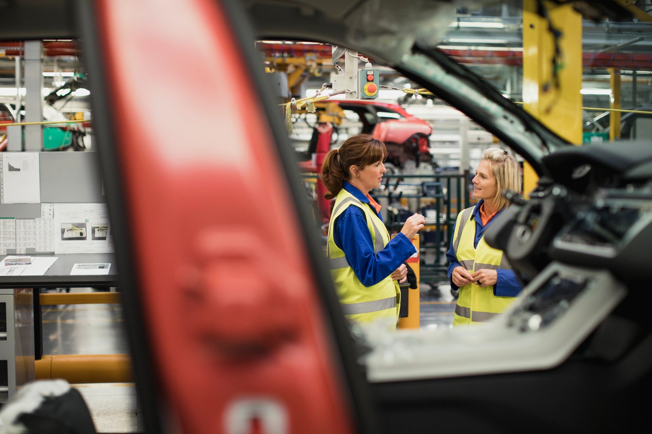 Factory workers in safety gear discussing on a production line